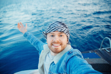 Smile happy man on keffiyeh or arabic shawl making selfie photo on yacht, concept trip boat sea
