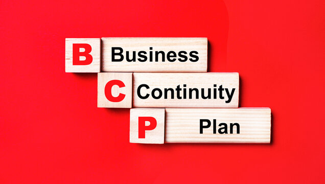 On a bright red background, wooden cubes and blocks with the text BCP Business Continuity Plan. Manufacturing of wooden toys.