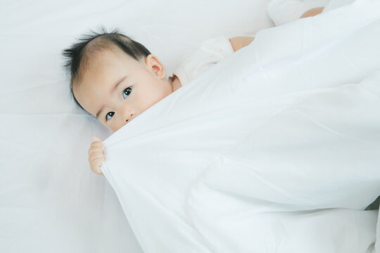 Cute Little Asian Baby On Bed With Soft Blanket Indoors