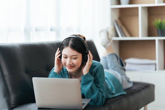 Beautiful Smiling Young Woman In Headphones Chatting Via Laptop Computer Video Call At Home