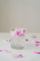 transparent glass with gin tonic and floral petals on white surface isolated on grey.