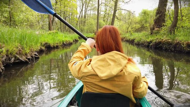 Outdoor Woman with Yellow Coat in Kayak on a River in Stunning Nature