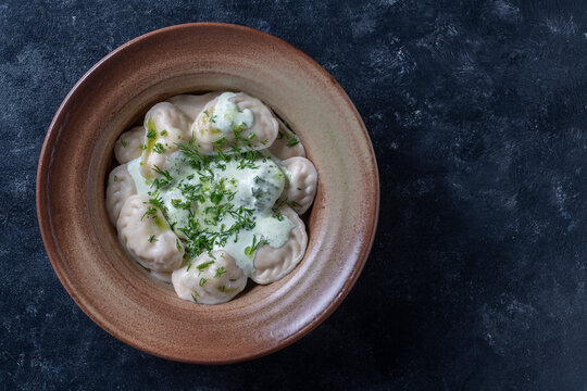 Appetizing dumplings stuffed with potatoes and mushrooms with sour cream and green dill