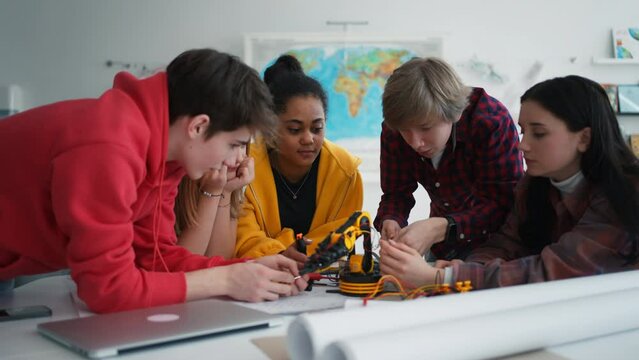 Group of students building and programming electric toys and robots at robotics classroom