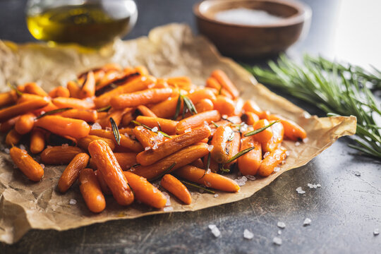 Roasted baby carrots with salt and rosemary on baking paper.
