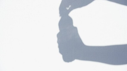 Closeup view 4k video footage of hand of anonymous person holds bottle of fresh water isolated on white background. Grey shadow silhouette of female arm with plastic bottle in hand. Woman opens bottle