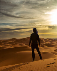 Fototapeta na wymiar silhouette of a man walking in the desert - Merzouga, Morocco