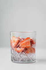 close up view of glass with fresh strawberry tonic on white surface isolated on grey.