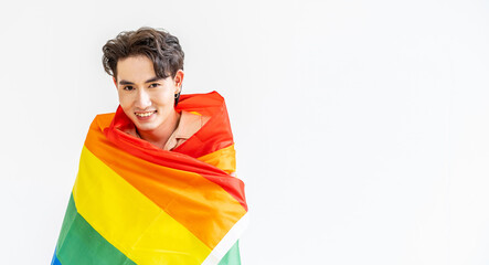 Portrait of transgender or gay man smiling in front of camera taking cover with lgbt flag on white background with copy space. People lifestyle fashion lgbtq concept