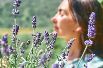 Defocused happy face of woman behind blooming scented organic lavender flowers for natural herbal...