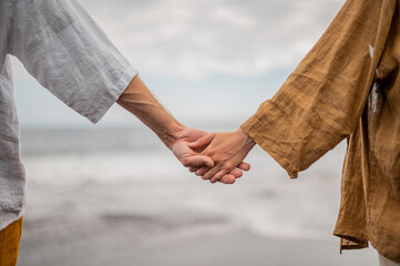 Young couple holding hands on a beach, no faces
