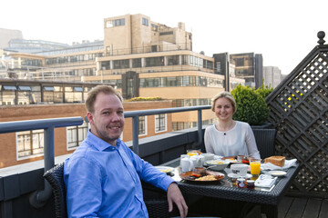 Couple having breakfast on a roof terrace in the big city
