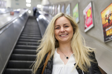 Pretty Blonde Woman Smiling on an Escalator into the Subway