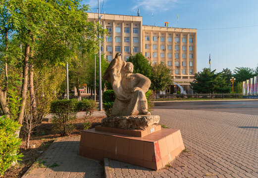 Elista, Russia - August 27, 2021: Sculpture of a berkutchi with a golden eagle on his hand against the background of the city administration.