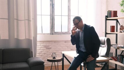 Young successful businessman has a phone call in the office or at home. The man is excited and happy, a successful solution to the issue, a good deal. The emotional reaction of victory.