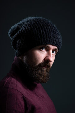 dramatic portrait of millennial in black knitted hat and sweater on dark background