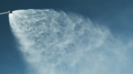 Snowgun sprays artificial snow against blue sky at ski resort in sunny day. Snow cannon by water through snow cannon for cover ski slopes. No people. Snowmaking system sprayes frost