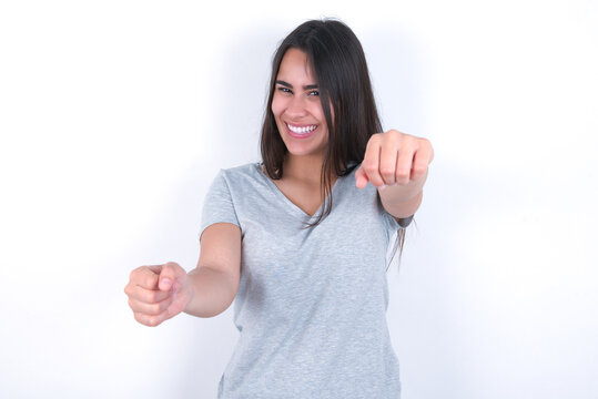 Young beautiful brunette woman wearing grey T-shirt over white wall  imagine steering wheel helm rudder passing driving exam good mood fast speed