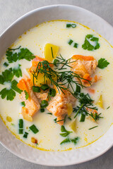 Norwegian salmon red fish soup with vegetables, herbs and cream, top view ,close up