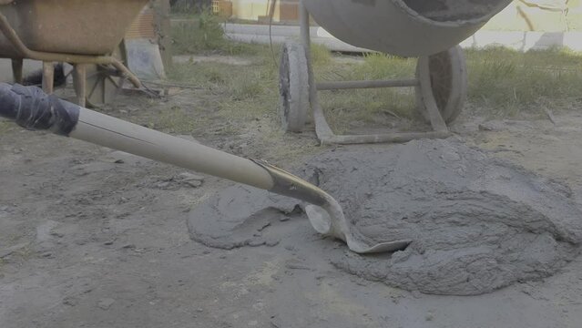 Placing the concrete mortar in the bucket with the shovel
