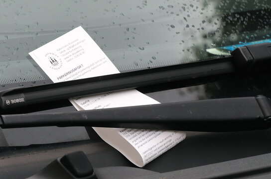 Copenhagen, Denmark - June 14, 2022: Close-up view of a parking fine attached to the vheicle windscreen wiper.