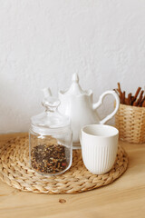 White ceramic teapot and cup on a wooden table. Front view.