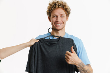 Young ginger man showing thumb up while posing with t-shirt