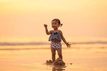 baby girl with happy time play on sand in evening time with beautiful sunset light