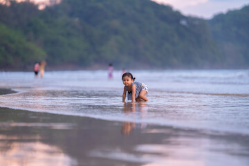 baby girl with happy time run and walk play on beach and wave sea in evening time with beautiful sunset light