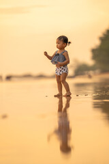 baby girl with happy time play on sand in evening time with beautiful sunset light