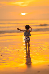 baby girl back view with freedom emotional happy time stand on beach in evening time with beautiful sunset light