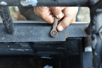 An image of an elderly man's hand repairing an old metal material.
