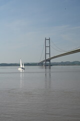 sailing boat traveling under the Humber Bridge on the river Humber Hessle. UK