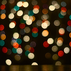 Christmas background is a dark table and blurred multicolored lights in the background.