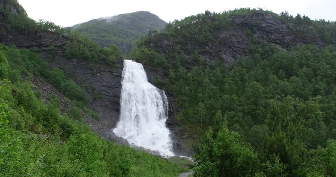 Wonderful landscapes in Norway. Hordaland. Beautiful scenery of Fossen Bratte waterfall. River Eikedalselva. Hardanger. Mountains and trees on rocks in background. 4K UHD 59,94fps ProRes 422 HQ 10 bit
