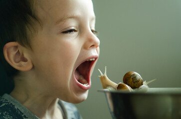 The little boy opened his mouth in front of the snails. Baby food. Veganism. Raising children and treating animals
