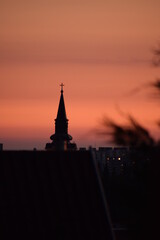 Church tower at the sunset with some rooftop in the front