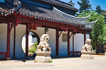 Entrance to a Chinese garden with two stone lions and a circular doorway