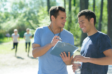 sports coach showing stopwatch to male athlete