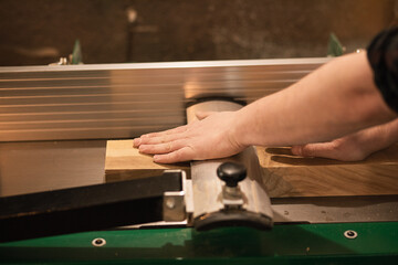 Close-up of carpenter hands in work, pressing down, fixing and work accurate with wood cutting machine in the workshop,