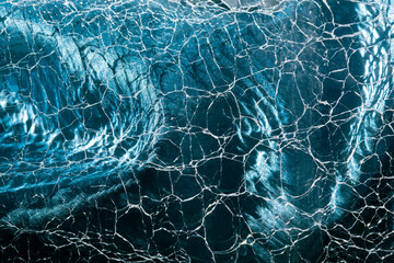 Blue abstract texture background. Silk material looks like clear water waves in sunshine rays, through cracked glass surface. Beautiful, creative, stylish backdrop for design. Selective soft focus