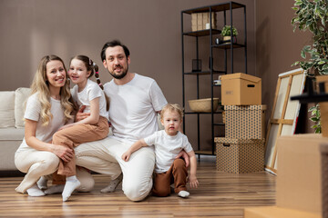 A family on moving day. An attractive young woman and a handsome bearded man, along with their adorable daughter and son, are enjoying their move to a new home.