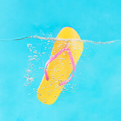 Vibrant yellow and pink flip flop water splash. Summer minimal concept. Creative trendy vacation aesthetic. Blue fun beach party background.