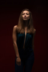 Beautiful lady girl against dark red background. Brunette girl wearing fancy shirt looking at camera..