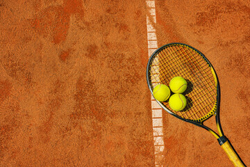  A yellow tennis ball and tennis racket lies on the clay court. - obrazy, fototapety, plakaty