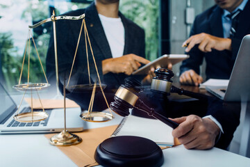 Justice and law concept.Male judge in a courtroom with the gavel, working with, computer and docking keyboard, eyeglasses, on table in morning light