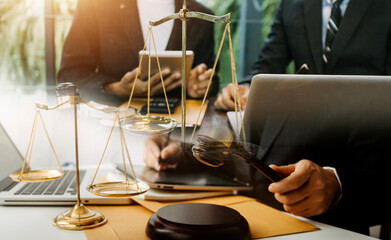 Justice and law concept.Male judge in a courtroom with the gavel, working with, computer and docking keyboard, eyeglasses, on table in morning light