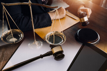 Justice and law concept.Male judge in a courtroom with the gavel, working with, computer and docking keyboard, eyeglasses, on table in morning light