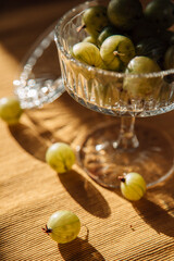 Juicy green gooseberries are lying on the table, served berries, berry snack or breakfast, vintage retro plate with gooseberries in the sun, summer local berries