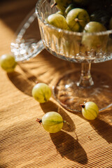 Juicy green gooseberries are lying on the table, served berries, berry snack or breakfast, vintage retro plate with gooseberries in the sun, summer local berries